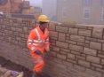 Random stone in a boundary wall, built for privacy, being jointed to match in with adjoining new-build properties