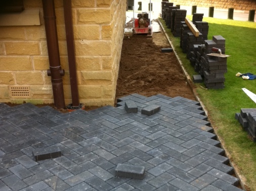 Continuation of a block paving patio area forming metre wide path ready for the ground to be compressed using the whacker plate